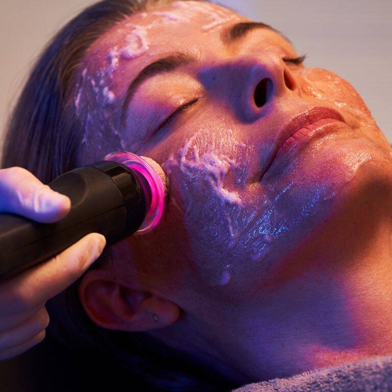 Woman smiling while receiving a GLO2Facial