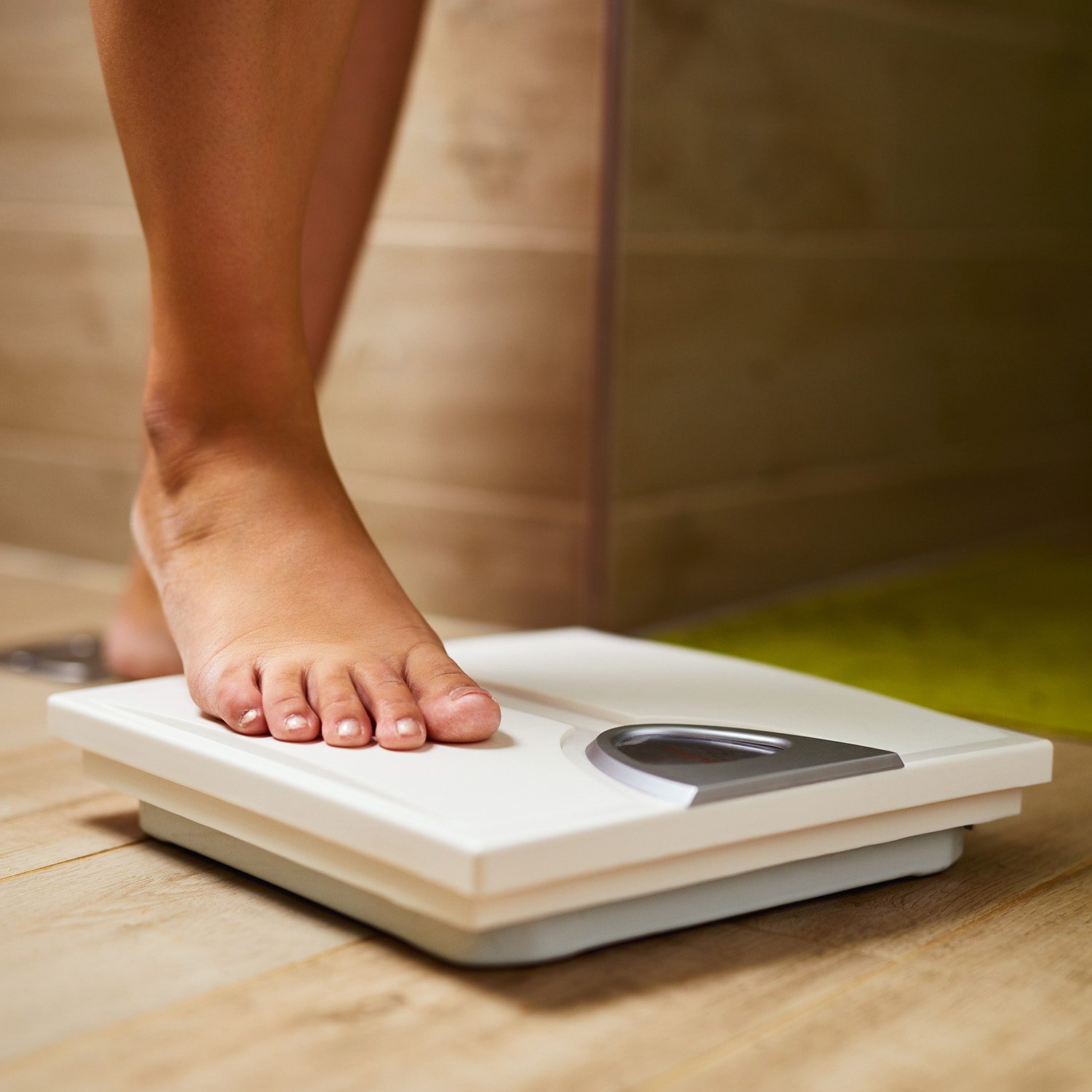 woman stepping on scale for weight loss measurement